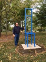 Artist Gary Kulak standing next to his sculpture Blue Square Back