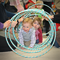 Children crawling through hula-hoops